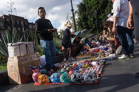 A street vendor sells souvenirs to tourists near the National Cathedral in Mexico City